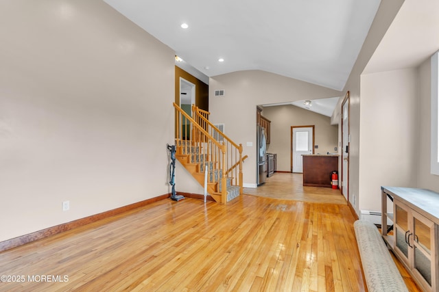 entryway with a baseboard heating unit, baseboards, light wood-type flooring, stairs, and vaulted ceiling