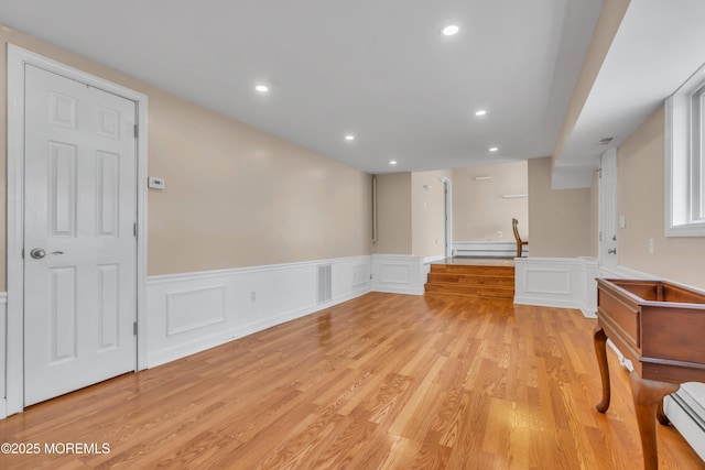 interior space featuring baseboard heating, light wood-style flooring, a baseboard heating unit, and visible vents