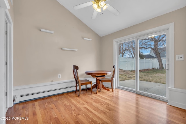 dining room featuring vaulted ceiling, baseboard heating, a ceiling fan, and wood finished floors