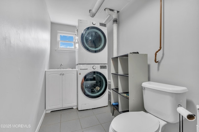 laundry area with light tile patterned floors, stacked washer / drying machine, laundry area, and a sink