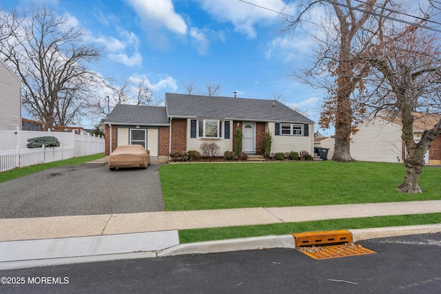 view of front facade featuring brick siding, a shingled roof, a front yard, and fence