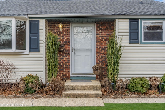 property entrance featuring brick siding and roof with shingles