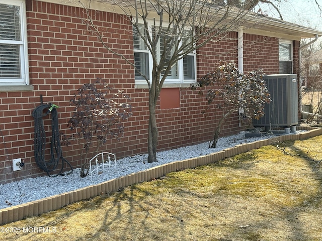 view of side of home with brick siding and central AC unit