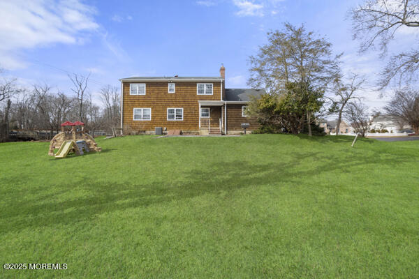 502 Monmouth Rd, West Long Branch, NJ 07764 - rear view of property with central air condition unit, a playground, a lawn, and a chimney