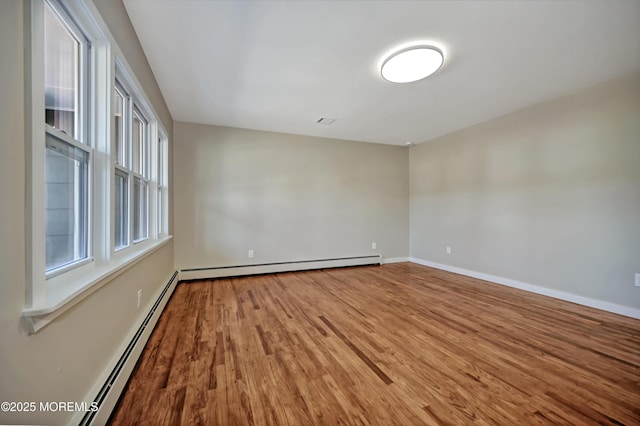 spare room with wood finished floors, baseboards, and a baseboard radiator