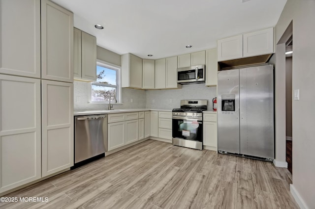 kitchen featuring a sink, stainless steel appliances, light wood-style floors, and light countertops