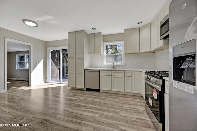 kitchen with light wood-style flooring, a sink, stainless steel appliances, light countertops, and a baseboard heating unit