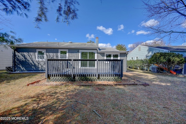 back of house featuring a yard, a deck, and a chimney