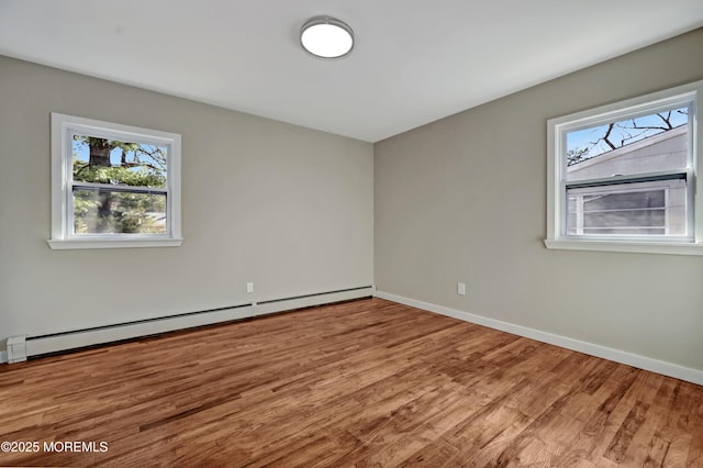 empty room featuring baseboard heating, baseboards, and wood finished floors