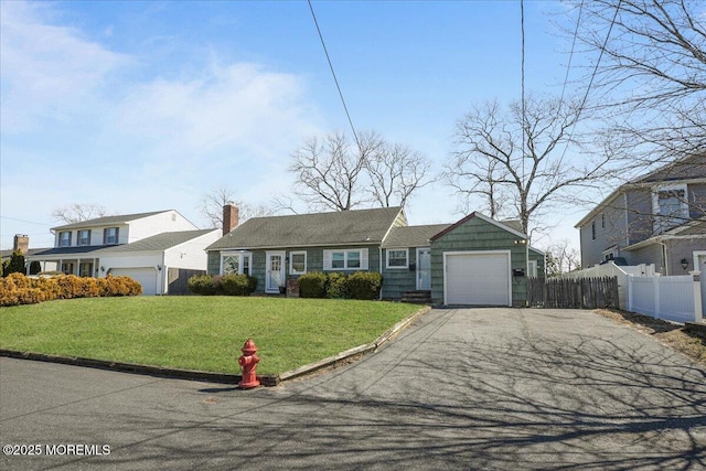 view of front facade featuring driveway, an attached garage, a front yard, and fence