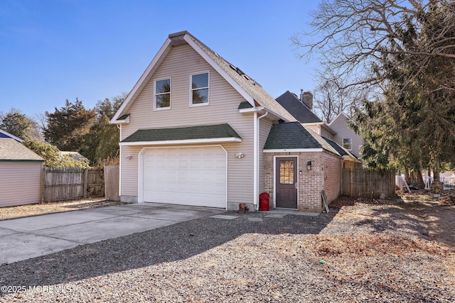 traditional-style home featuring concrete driveway, fence, a garage, and roof with shingles