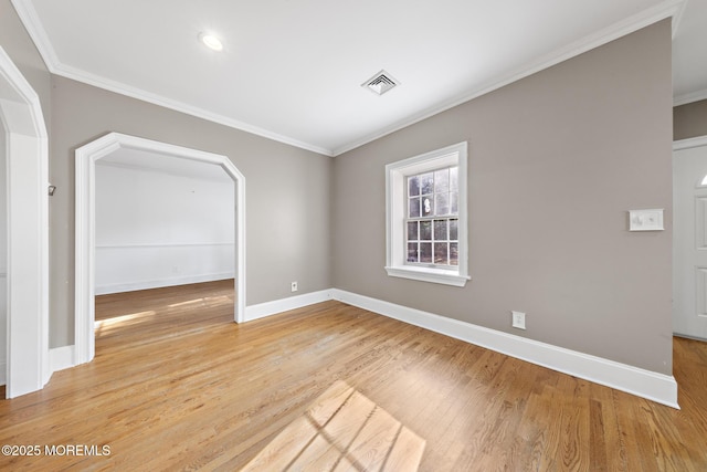 spare room with visible vents, baseboards, crown molding, and light wood finished floors