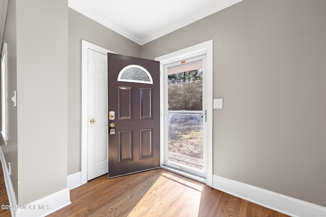 foyer entrance with wood finished floors, baseboards, and ornamental molding