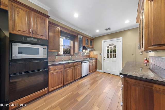 kitchen featuring under cabinet range hood, tasteful backsplash, appliances with stainless steel finishes, crown molding, and glass insert cabinets