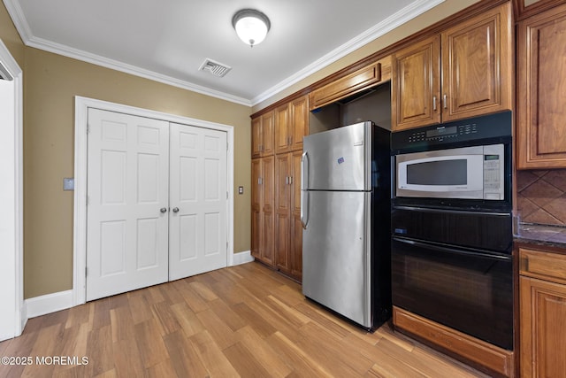 kitchen with brown cabinetry, visible vents, oven, and freestanding refrigerator