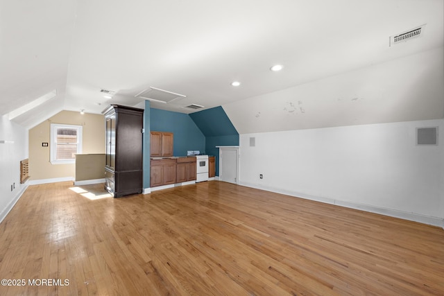 additional living space with visible vents, attic access, and light wood finished floors