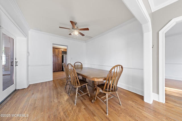 dining room with visible vents, baseboards, ornamental molding, light wood-style flooring, and a ceiling fan