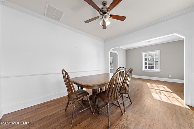 dining area with wood finished floors, baseboards, visible vents, arched walkways, and ornamental molding