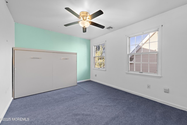 unfurnished bedroom featuring visible vents, multiple windows, carpet flooring, and baseboards