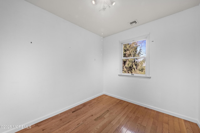 unfurnished room with visible vents, baseboards, and wood-type flooring