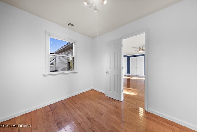 unfurnished bedroom featuring hardwood / wood-style floors, baseboards, and visible vents