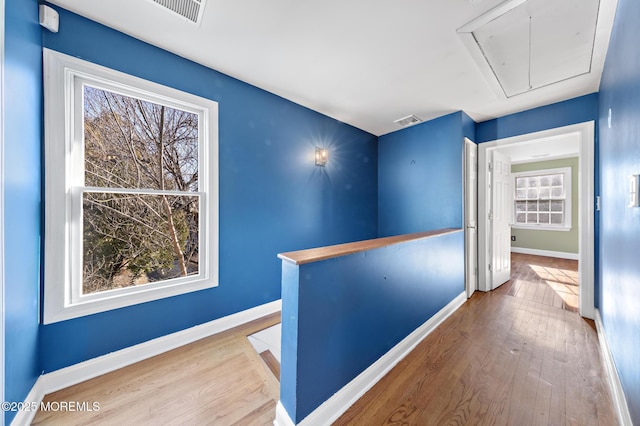 hall featuring a wealth of natural light, visible vents, attic access, and wood finished floors