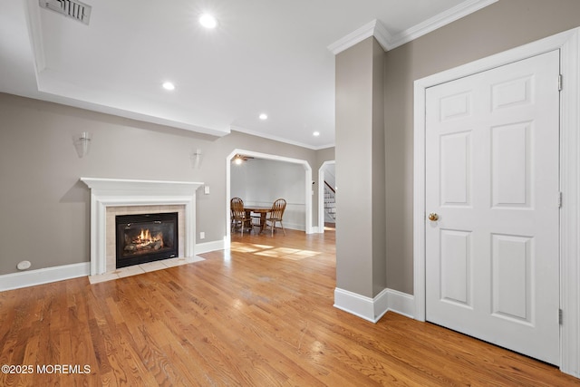 unfurnished living room with light wood finished floors, visible vents, crown molding, and baseboards