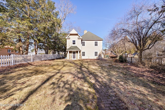 rear view of house with a fenced backyard, a lawn, and a chimney