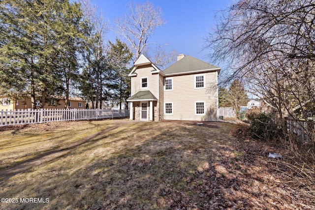 rear view of house featuring a lawn, fence private yard, and a chimney