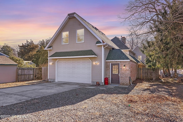 traditional-style home featuring a chimney, concrete driveway, brick siding, and fence