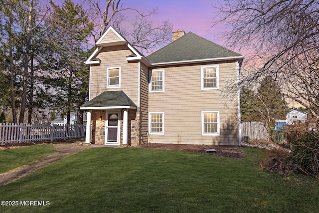 view of front of property featuring a yard, a shingled roof, a chimney, and fence