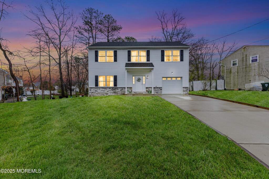 27 Sylvan Blvd, Howell, NJ 07731 - traditional-style house featuring a garage, stone siding, fence, a front lawn, and driveway