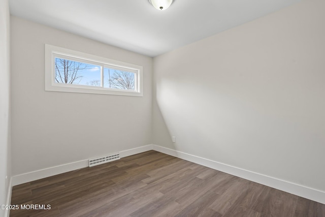 spare room with visible vents, baseboards, and dark wood-style floors