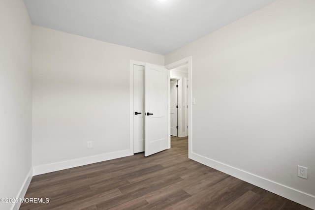 unfurnished room featuring baseboards and dark wood finished floors