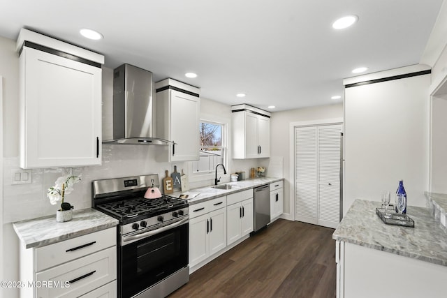 kitchen with a sink, dark wood finished floors, appliances with stainless steel finishes, wall chimney exhaust hood, and white cabinets