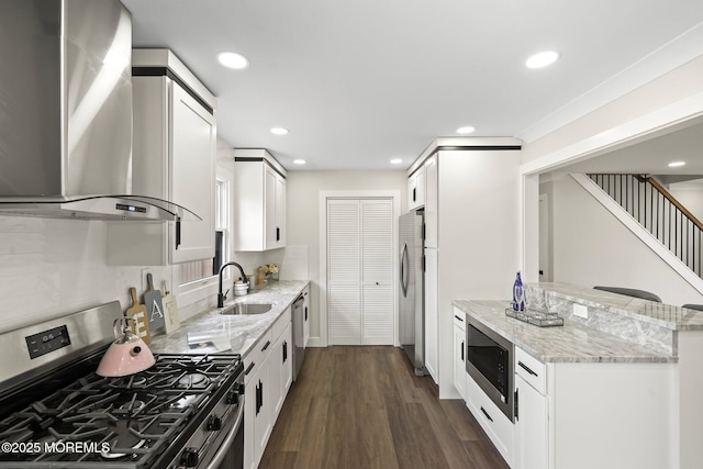 kitchen featuring dark wood-type flooring, light stone countertops, stainless steel appliances, wall chimney exhaust hood, and a sink