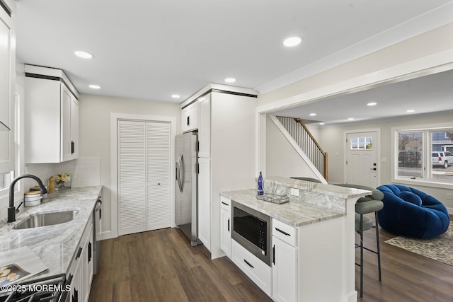 kitchen with dark wood-style flooring, appliances with stainless steel finishes, a kitchen bar, and a sink