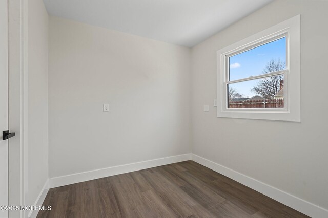 spare room featuring baseboards and dark wood-style flooring