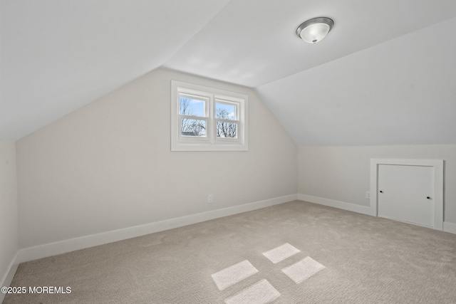 bonus room with lofted ceiling, light colored carpet, and baseboards