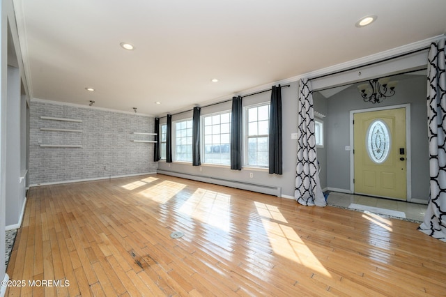 interior space featuring light wood-style flooring, baseboard heating, brick wall, and crown molding