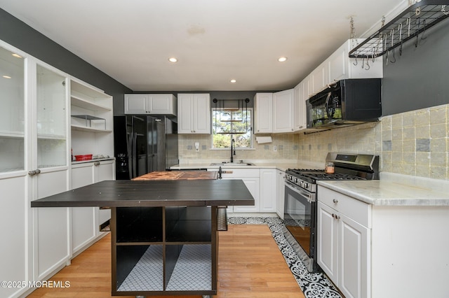 kitchen featuring a sink, white cabinets, black appliances, and open shelves