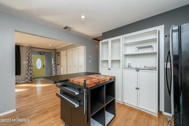 kitchen with open shelves, visible vents, light wood-style flooring, and freestanding refrigerator