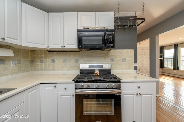 kitchen with tasteful backsplash, stainless steel range with gas stovetop, white cabinetry, and black microwave