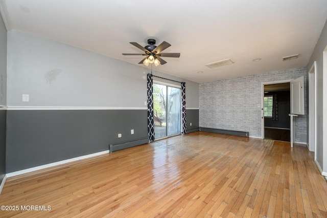 spare room with light wood-style flooring, brick wall, ceiling fan, and a baseboard radiator