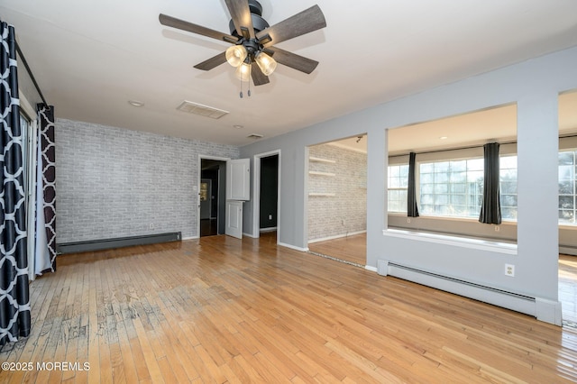 spare room featuring hardwood / wood-style flooring, visible vents, brick wall, and a baseboard radiator