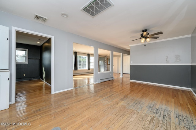 empty room with visible vents, baseboard heating, a baseboard heating unit, and light wood-style floors