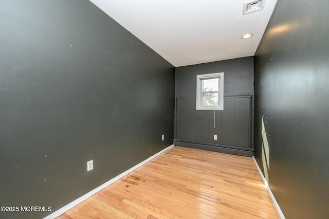 empty room with visible vents, baseboards, a baseboard heating unit, and light wood-style floors