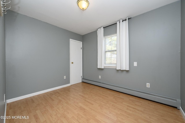 empty room with baseboards, baseboard heating, and wood finished floors