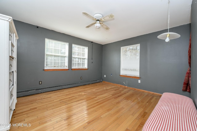 unfurnished bedroom featuring a baseboard heating unit, a ceiling fan, and light wood finished floors