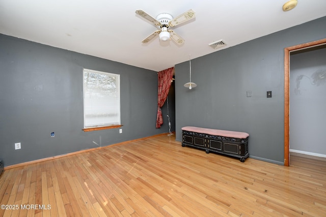 spare room featuring visible vents, baseboards, a ceiling fan, and hardwood / wood-style floors